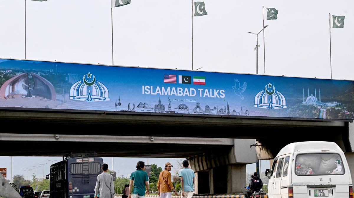 Boys walk under a digital screen displaying news of USIran peace talks along a road in Islamabad on April 10, 2026. (Farooq Naeem/AFP/Getty Images/TNS)