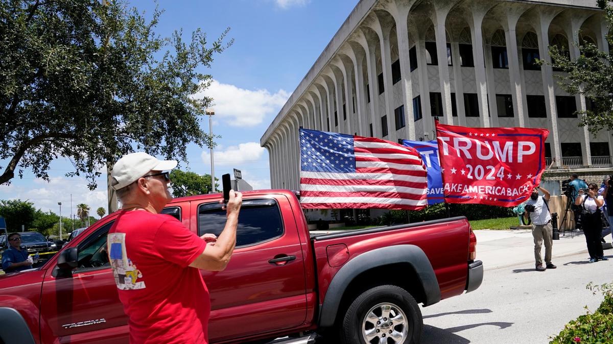 Un vehículo con banderas en apoyo al ex presidente Donald Trump conduce el jueves 18 de agosto de 2022, fuera del juzgado federal Paul G. Rogers en West Palm Beach, Florida.