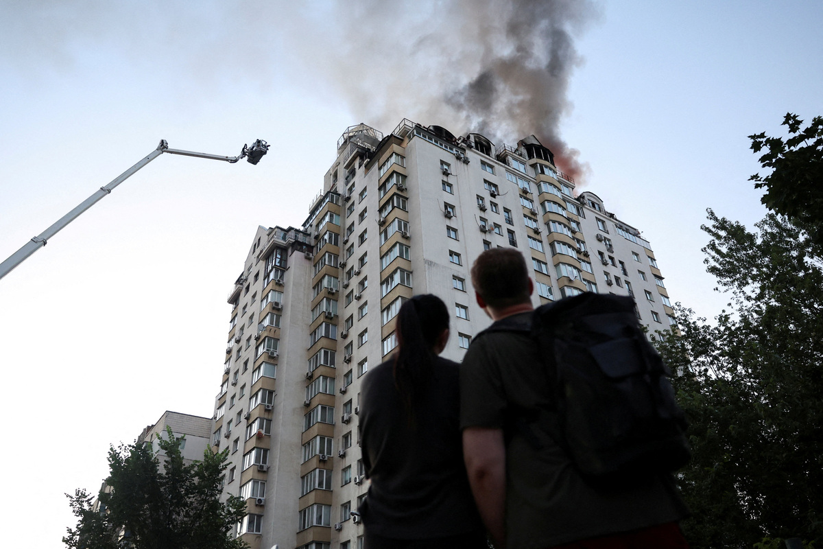 Residents look on as firefighters work at the site of an apartment building damaged during overnight Russian missile and drone strikes, amid Russia’s attack on Ukraine, in Kyiv, Ukraine, July 2, 2026. REUTERS/Alina Smutko