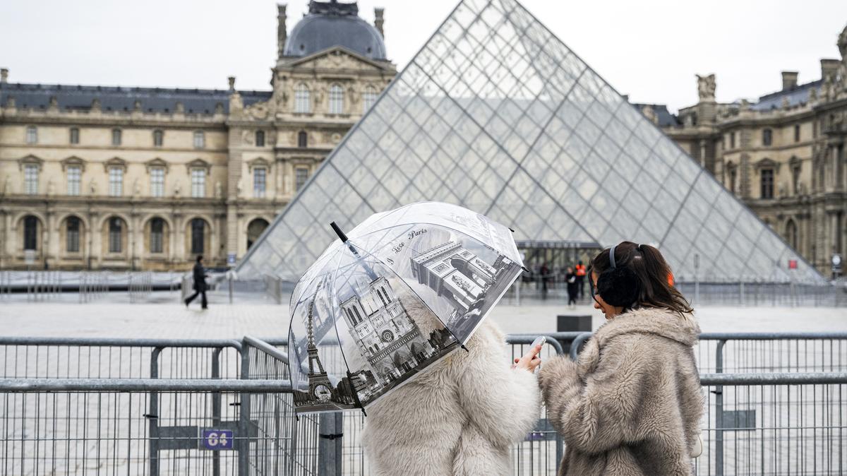 Tourists stand next to barriers blocking the plaza with the Louvre Pyramid, designed by Chinese-US architect Ieoh Ming Pei, as the Louvre Museum is closed due a strike in Paris on Jan. 12, 2026. The Louvre museum was forced to close on Jan. 12, 2026, after its staff, who have been on strike since mid-December in a bid to secure better working conditions, decided to continue their action, learned from the museum and trade unions. (Martin Lelievre/AFP/Getty Images/TNS)