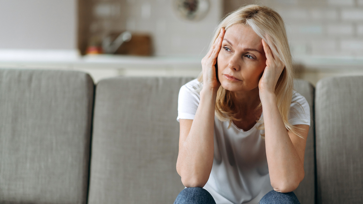 A stock image of a woman looking unhappy with her head in her hands. 