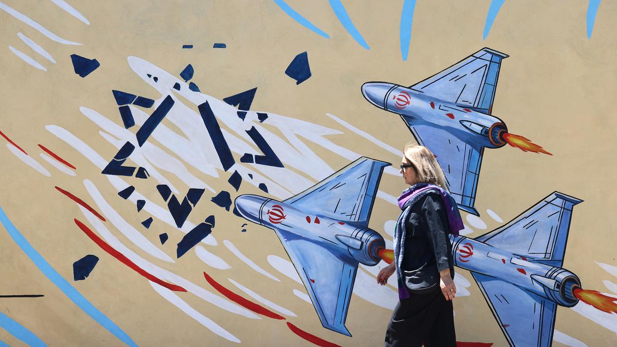 An Iranian woman walks past an anti-US and anti-Israel mural painted on a wall in the capital Tehran on May 10, 2026. The spokesman for the Iranian parliament's national security commission warned the United States on May 10, against any attacks on vessels in Gulf waters, saying Iran's restraint was over. (Atta Kenare/AFP via Getty Images/TNS)