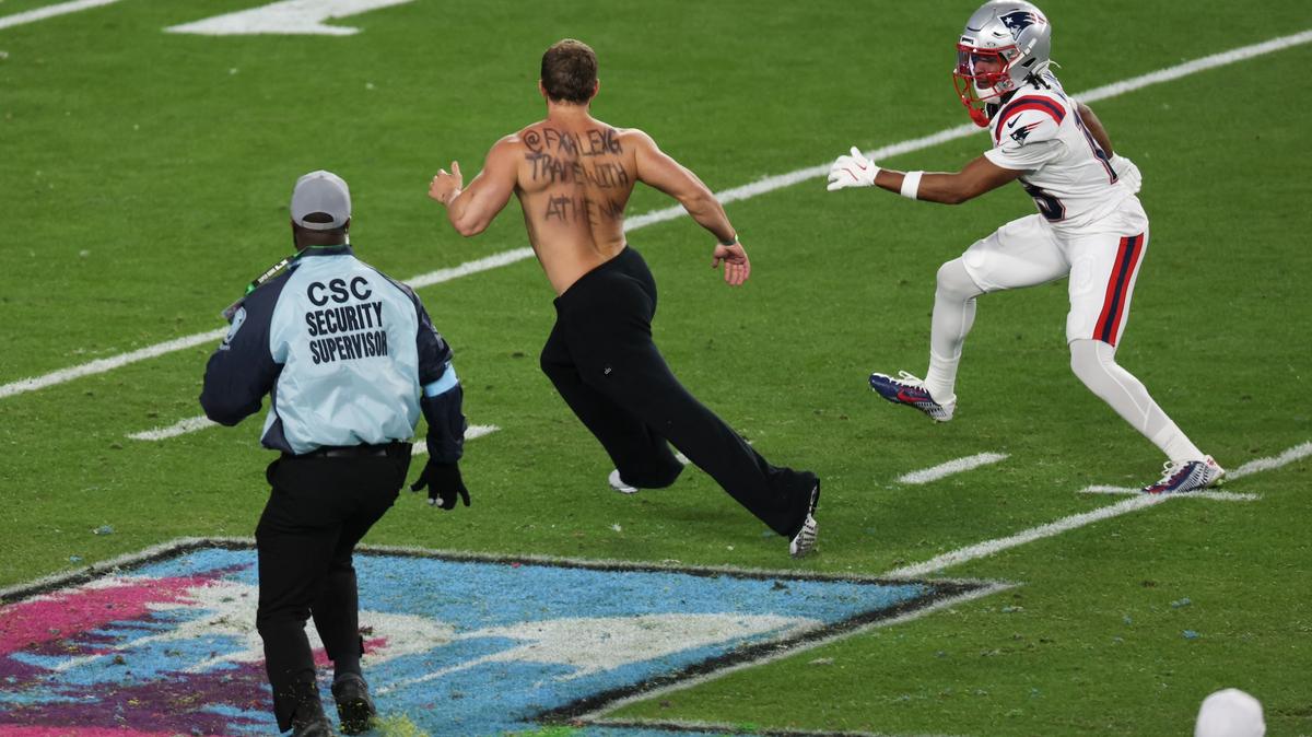 New England Patriots’ wide receiver #18 Kyle Williams helps security coral a streaker during Super Bowl LX between the New England Patriots and the Seattle Seahawks at Levi's Stadium in Santa Clara, California on February 8, 2026. (Photo by Patrick T. Fallon / AFP)