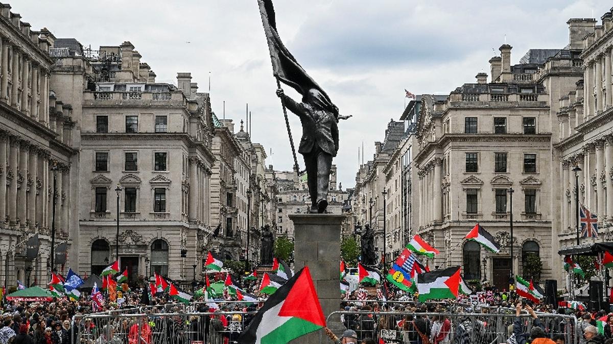 People hold Palestinian flags next to a statue, depicting a figure carrying a flag covering their face and stepping off a plinth, by British street artist Banksy during a march, held by Palestine Solidarity Campaign, to mark the 78th anniversary of the Nakba and against the "Unite the Kingdom" rally taking place in London organised by British anti-immigration activist Stephen Yaxley-Lennon, also known as Tommy Robinson, in London, Britain, May 16, 2026.