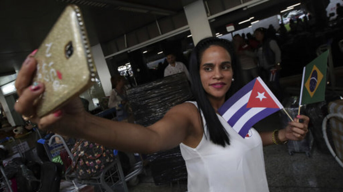 Una doctora cubana sosteniendo banderas de Cuba y Brasil se toma una selfie antes de que ella y otros médicos de su país regresen a casa desde el aeropuerto de Brasilia, Brasil, el jueves 22 de noviembre de 2018.