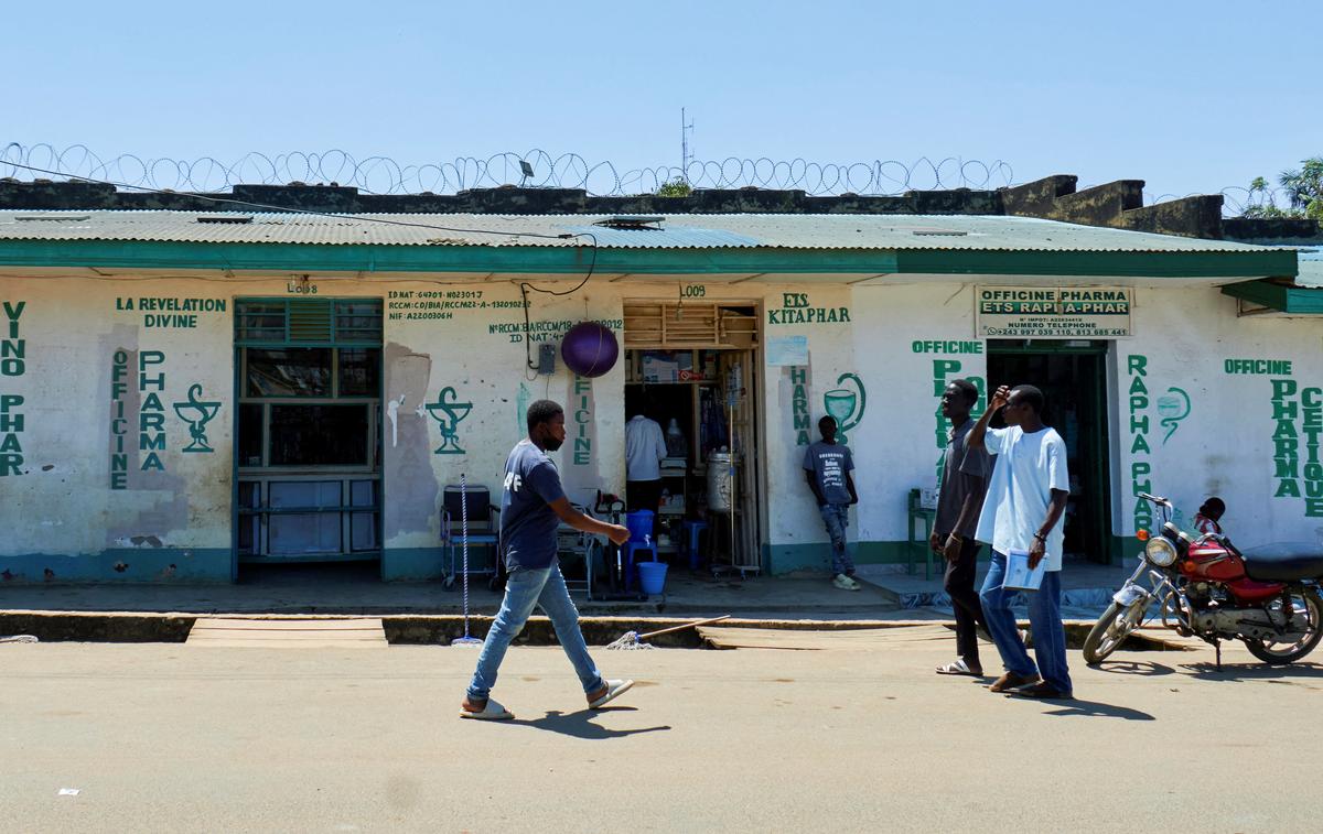 Congolese people walk past open pharmacies along a street, as aid agencies intensify efforts to contain a new Ebola outbreak involving the Bundibugyo strain, in Bunia, Ituri province, Democratic Republic of Congo, May 22, 2026. REUTERS/Gradel Muyisa Mumbere