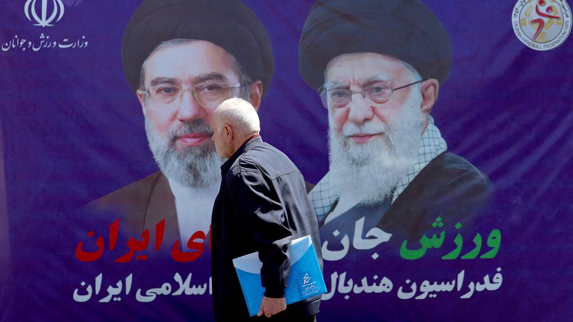 A man walks past a banner with pictures of Iran's slain supreme leader Ayatollah Ali Khamenei (R) and his son and successor Mojtaba Khamenei, installed along a street in Tehran on April 15, 2026. The United States has not formally agreed to extend its two-week ceasefire with Iran, a senior official said on April 15, after reports that President Donald Trump's administration had consented in principle to lengthen the truce. (AFP/Getty Images/TNS)