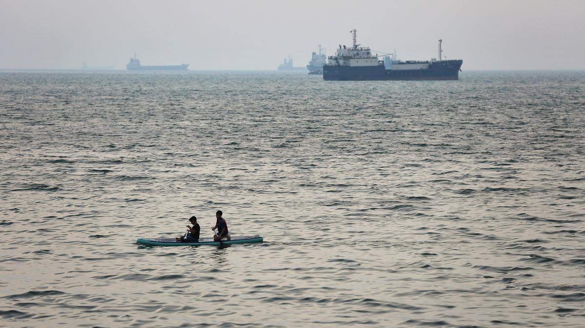 Two boys paddle-board in the sea as ships are anchored near the shoreline on Wednesday, April 22, 2026, in Bandar Abbas, Iran. Bandar Abbas is a port city and the capital of Hormozgan Province, along the Persian Gulf and Strait of Hormuz. (Getty Images/TNS)