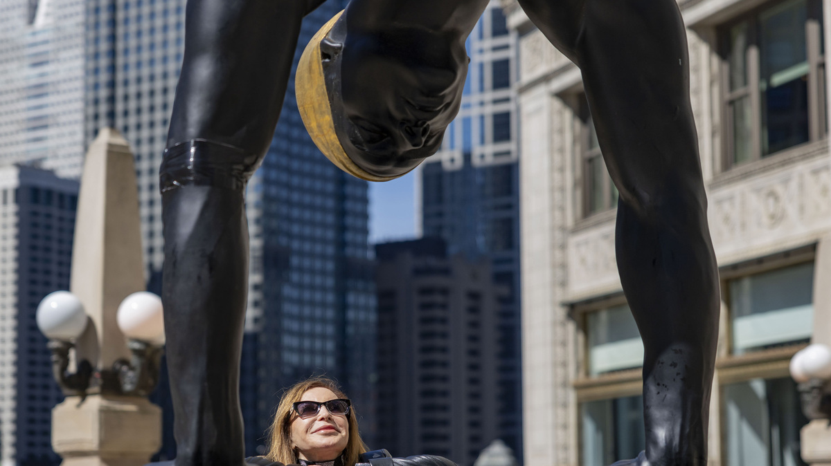 Artist Carole Feuerman looks up at her sculpture titled The Golden Mean on Tuesday, June 2, 2026, along North Michigan Avenue in Chicago. A series of 10 swimmers in the outdoor art exhibit will line the Magnificent Mile through November.