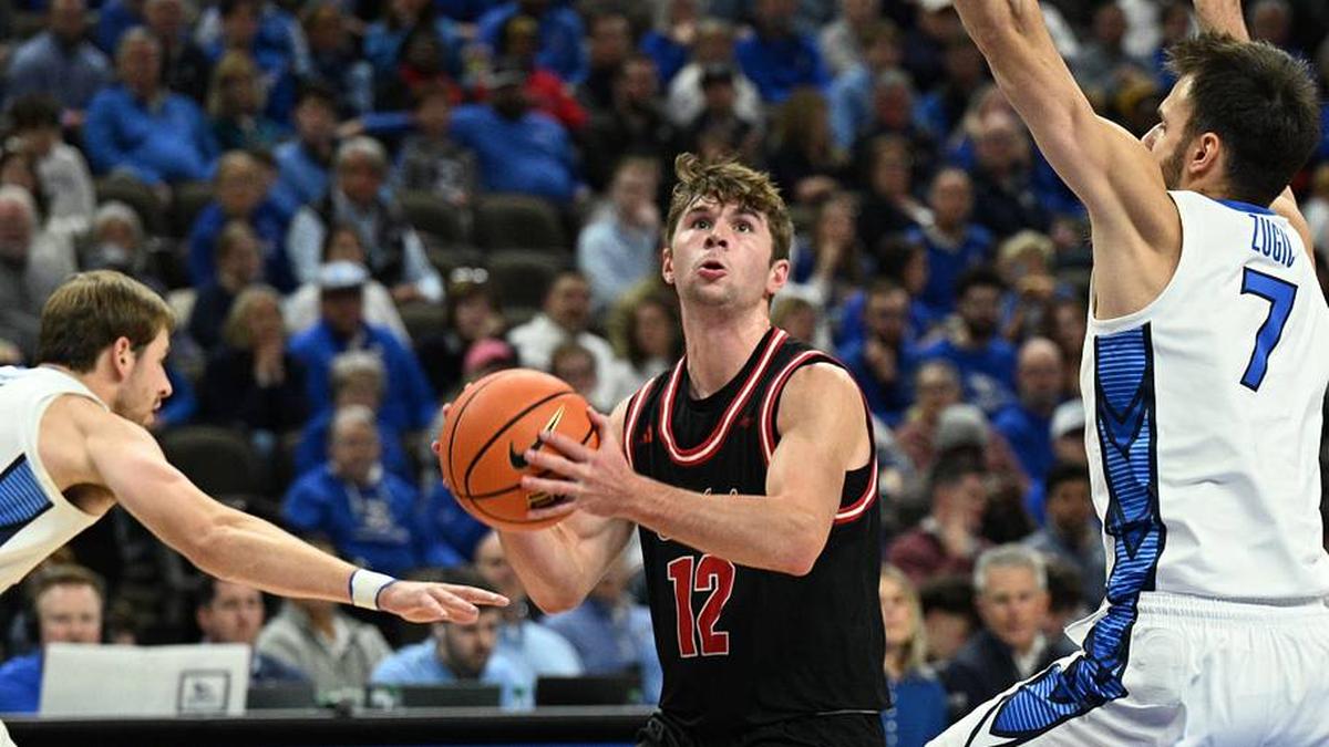  Nov 5, 2025; Omaha, Nebraska, USA; South Dakota Coyotes guard Isaac Bruns (12) drives against Creighton Bluejays forward Isaac Traudt (41) and Fedor Zugic (7) during the first half at CHI Health Center Omaha. Mandatory Credit: Steven Branscombe-Imagn Images | Steven Branscombe-Imagn Images 
