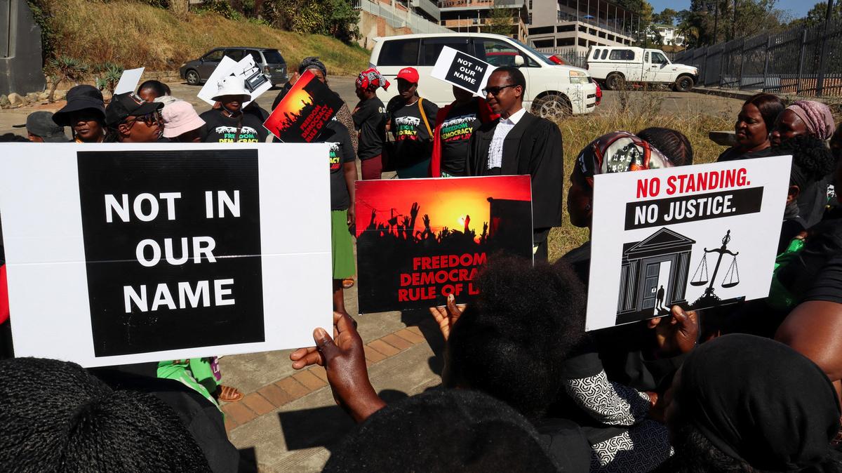 Protesters hold placards as lead applicant and lawyer Mzwandile Masuku addresses them outside the court, after today's hearing was postponed, in Mbabane, Eswatini, August 22, 2025. Activists are challenging a secretive agreement with former U.S. President Donald Trump's administration to accept third-country deportees, which they argue is unconstitutional. REUTERS/Zakhele Mabuza