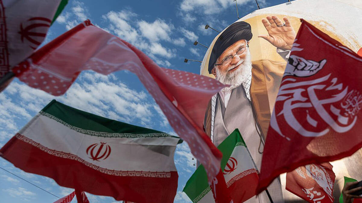 Flags are waved below the portrait of Iran's slain Supreme Leader Ayatollah Ali Khamenei during the third day of his funeral ceremonies in Tehran on Monday. Citing two U.S. officials, Axios reported that Iran’s Revolutionary Guards fired at least two missiles at commercial ships transiting through the Strait of Hormuz on Monday night.