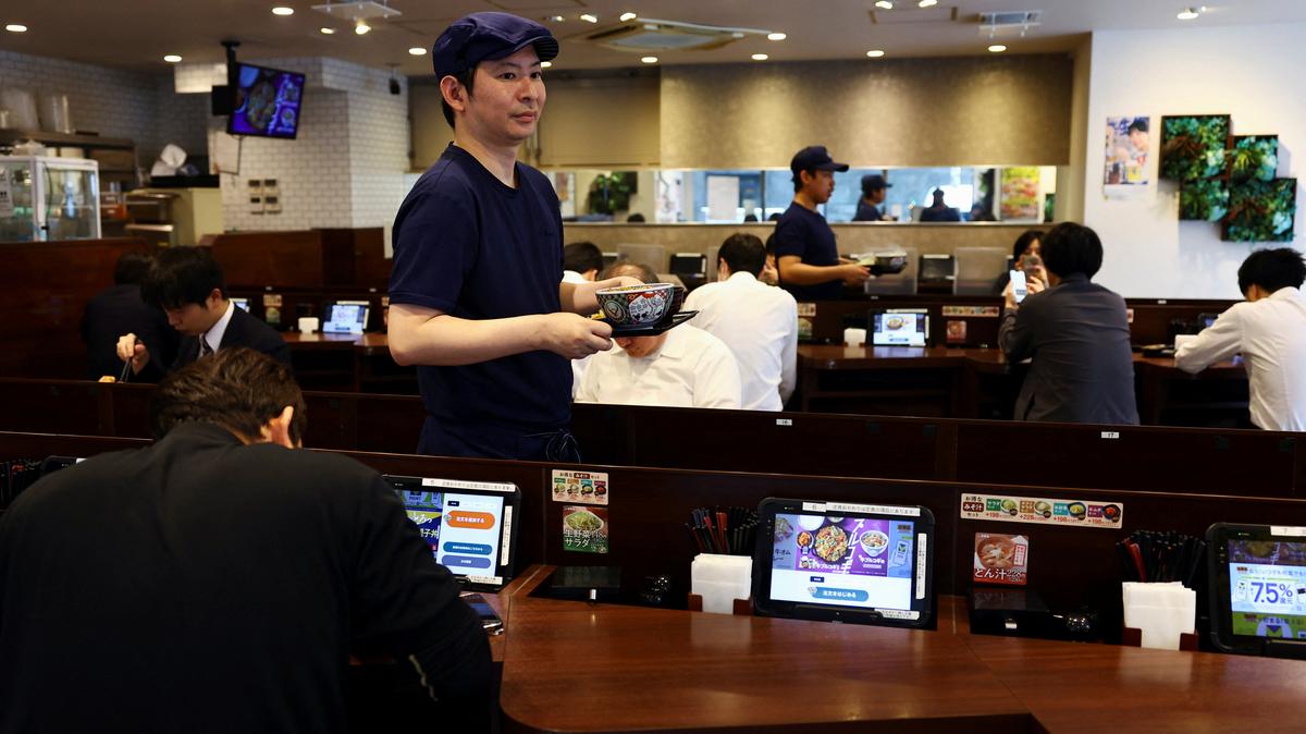 Staff members serve 'gyudon' beef bowls to customers inside Yoshinoya restaurant in Tokyo, Japan May 19, 2025.  REUTERS/Issei Kato