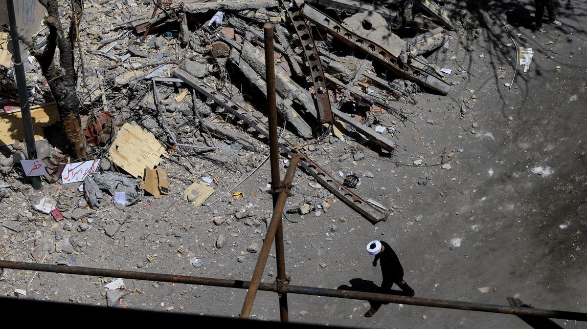 A cleric walks near a residential building damaged by a strike on March 4, in Tehran, Iran, April 14, 2026. REUTERS/Thaier Al Sudani/File Photo