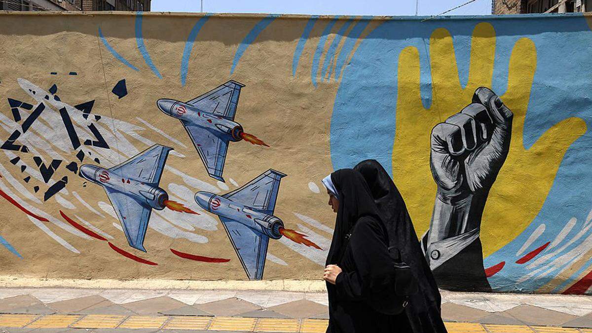 Iranian women walk past an anti-U.S. and anti-Israeli mural in Tehran on Wednesday. The Republican-led U.S. House of Representatives approved a resolution on Wednesday to block President Donald Trump from continuing the war against Iran, reflecting growing concern among members of his party about the three-month-old conflict.