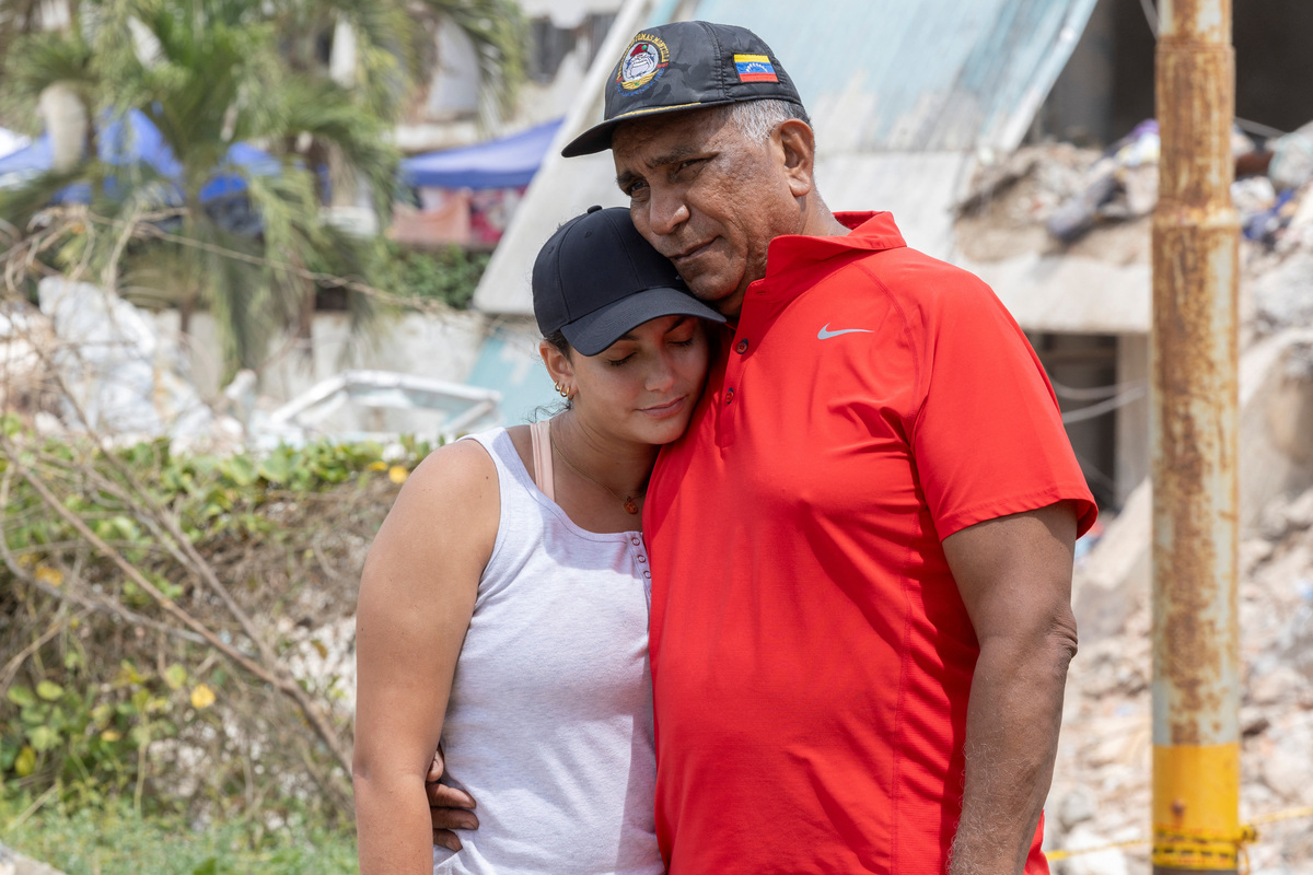 Maria Alejandra Sanz, 17, embraces her father, Alejandro Sanz, with the remains of their apartment building in the background in La Guaira, Venezuela, July 5, 2026. REUTERS/Ricardo Arduengo