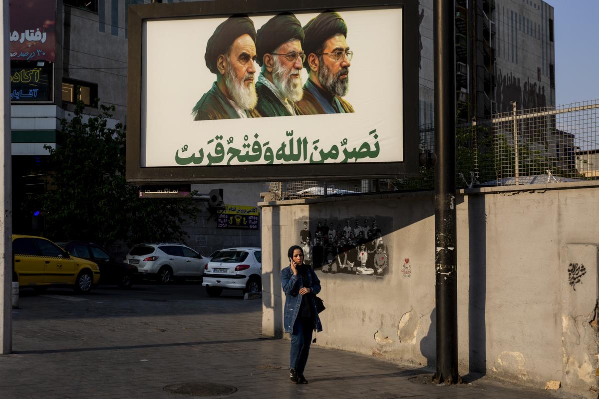 A woman walks by a billboard showing the three supreme leaders of Iran in Tehran, Iran, May 2, 2026. President Donald Trump and top American officials said on Tuesday, May 5, 2026, that a shaky cease-fire with Iran was holding despite new attacks by both sides after the American military launched an effort to reopen the Strait of Hormuz, which Iran has effectively shut down to most commercial ships. (Arash Khamooshi/The New York Times)