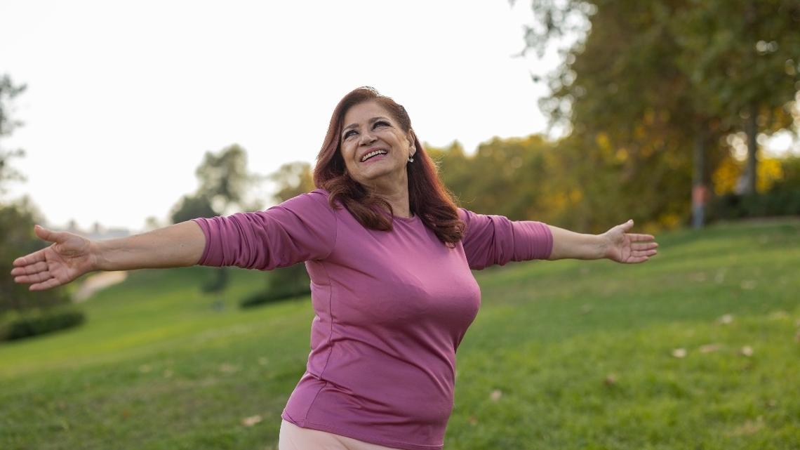 Mature overweight woman with raised arms enjoying in the nature.