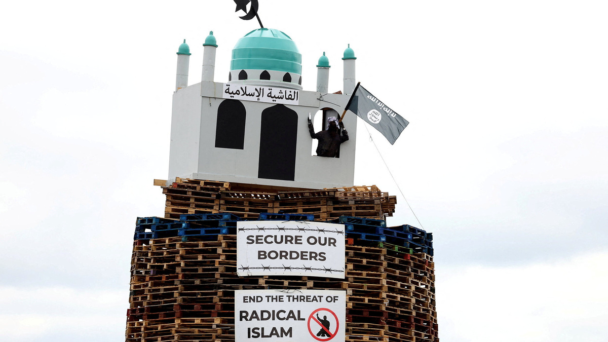 An effigy of a person holding a knife in a mosque stands atop the Moygashel bonfire ahead of its lighting as part of the annual bonfire events marking the 1690 Battle of the Boyne, in Moygashel, Northern Ireland, July 9, 2026. REUTERS/Cathal McNaughton