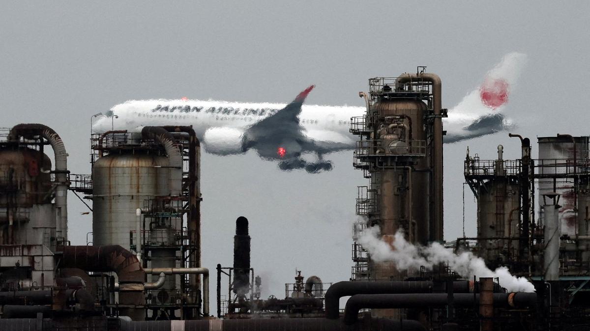 FILE PHOTO: A Japan Airlines (JAL) airplane flies past an oil refinery as it approaches to land at Tokyo's Haneda airport, as seen from a park in the Keihin Industrial Zone in Kawasaki, south of Tokyo, Japan, March 17, 2026. REUTERS/Issei Kato/File Photo