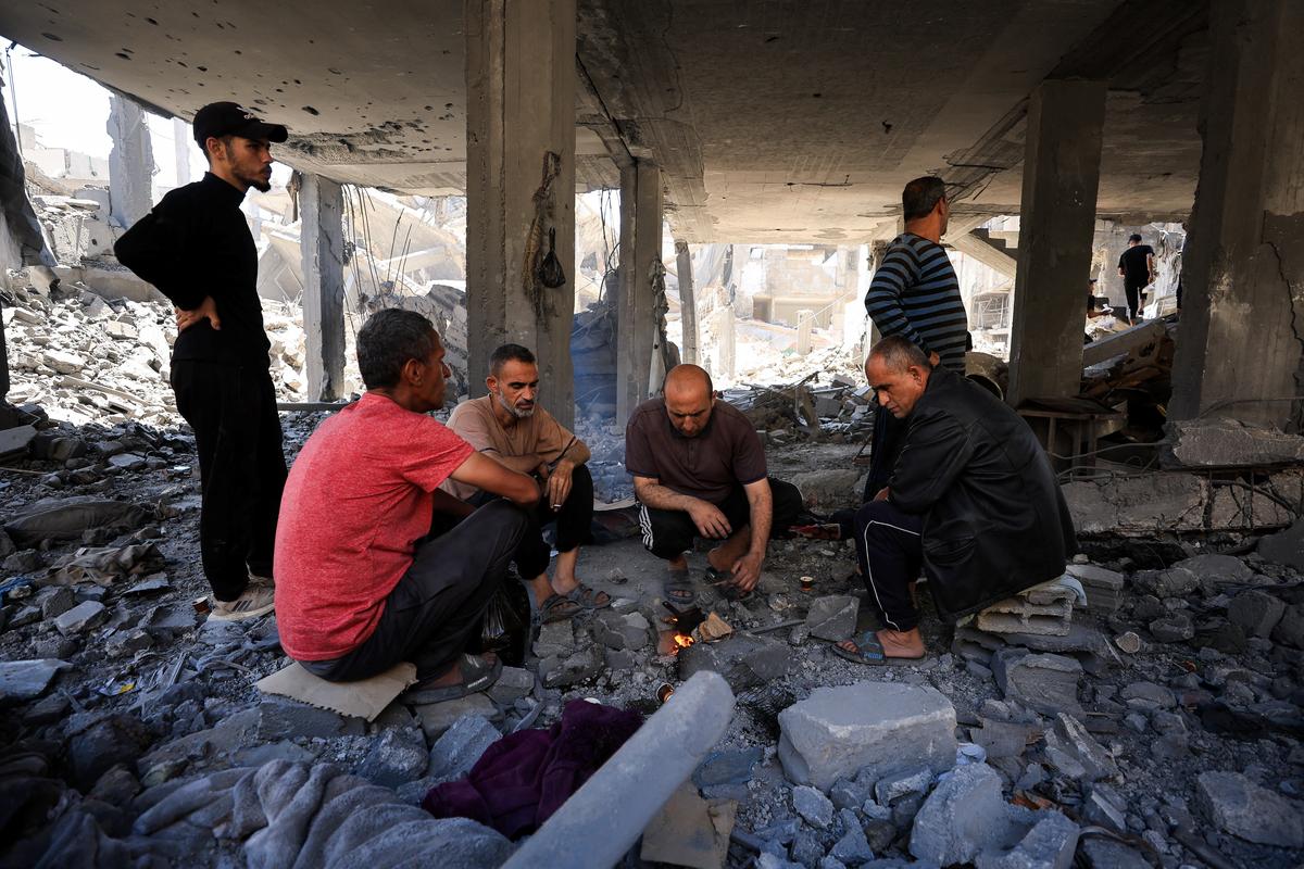 Palestinian men sit around the fire at the site of an Israeli strike on a house that was pre-warned by the Israeli military to evacuate, before the strike was carried out late on Thursday at Shati (Beach) refugee camp, in Gaza City, May 29, 2026. REUTERS/Dawoud Abu Alkas