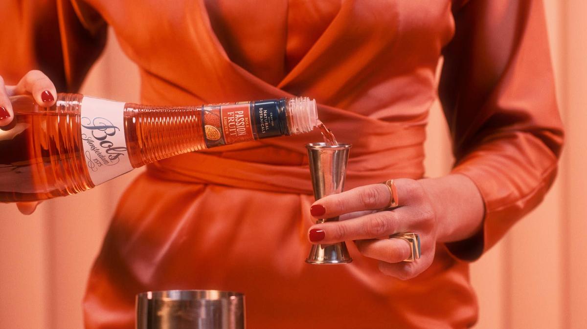 A woman dressed in orange pours Bols passion fruit liquor to make an exclusive cocktail for Holland America Line's Orange Party.