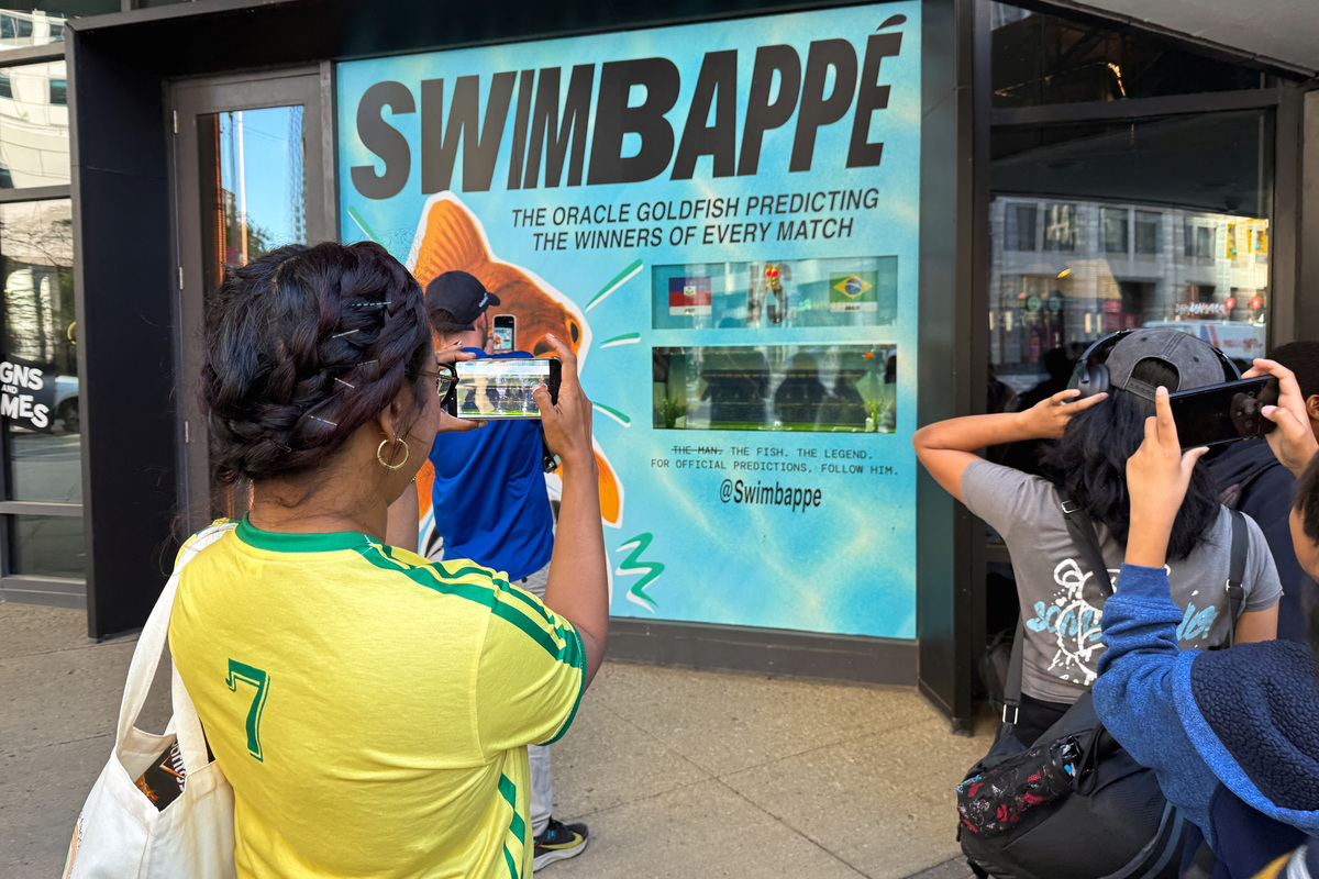 A crowd of soccer fans and children gather outside an office window on Wellington Street to watch Swimbappe, an oranda goldfish that makes daily World Cup match predictions, in Toronto, Ontario, Canada, June 19, 2026. Glenn's creative studio designed the soccer-themed tank activation to allow the fish to make daily World Cup match predictions. Picture taken with a mobile phone. REUTERS/Kyaw Soe Oo