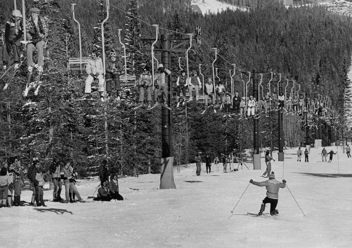  Breckenridge Ski Area. Skiers riding the chairlift watch the Telemark technique performed (1979).