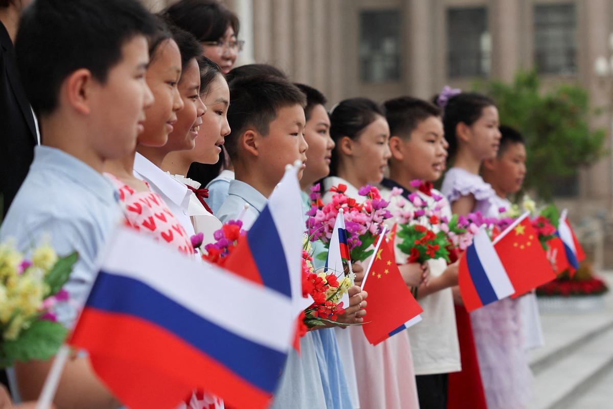 Children holding Russian and Chinese flags pose for a photo before a welcoming ceremony for Russian President Vladimir Putin at the Great Hall of the People in Beijing, China May 20, 2026. REUTERS/Maxim Shemetov/Pool