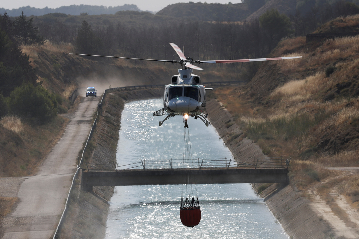 A firefighting helicopter loads water to battle wildfires affecting Zaragoza province, in Farasdues, Spain, July 16, 2026. REUTERS/Violeta Santos Moura