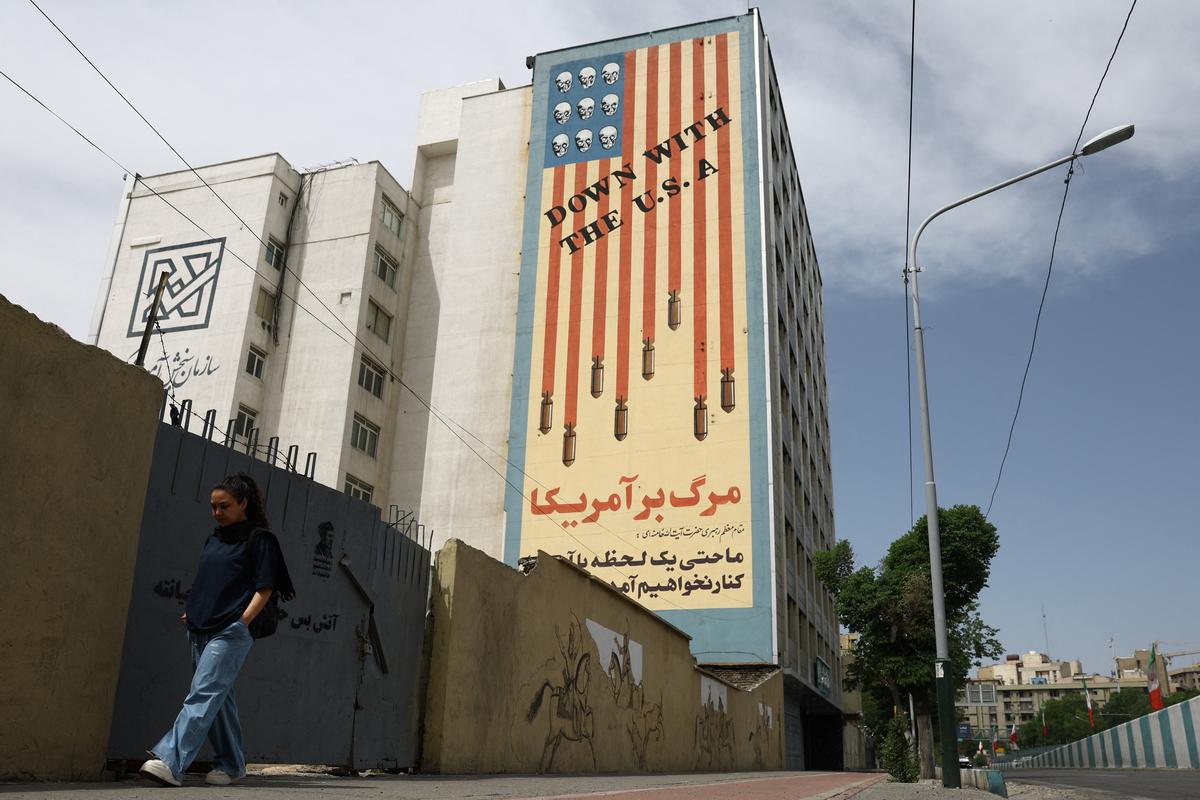 A woman walks past an anti-U.S. mural on a building in Tehran, Iran, May 8, 2026. Majid Asgaripour/WANA (West Asia News Agency) via REUTERS