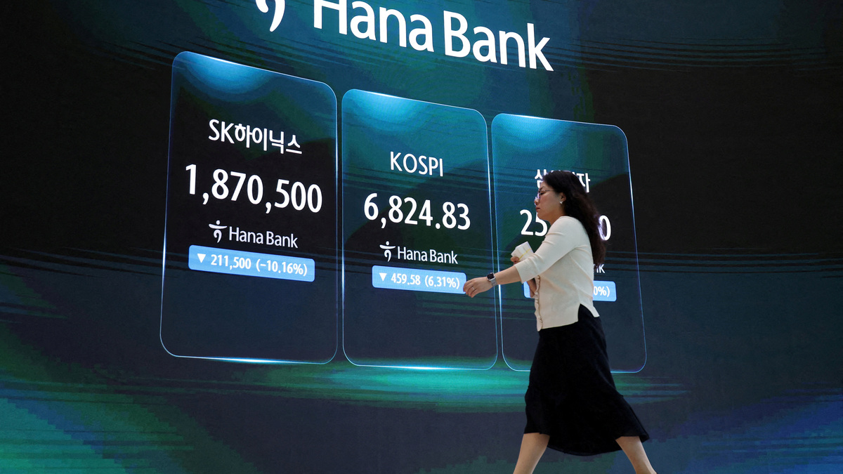 A currency dealer walks in front of an electronic board displaying SK Hynix and Samsung Electronics stock prices and the Korea Composite Stock Price Index (KOSPI) at the dealing room of a bank in Seoul, South Korea, July 16, 2026. REUTERS/Kim Hong-Ji