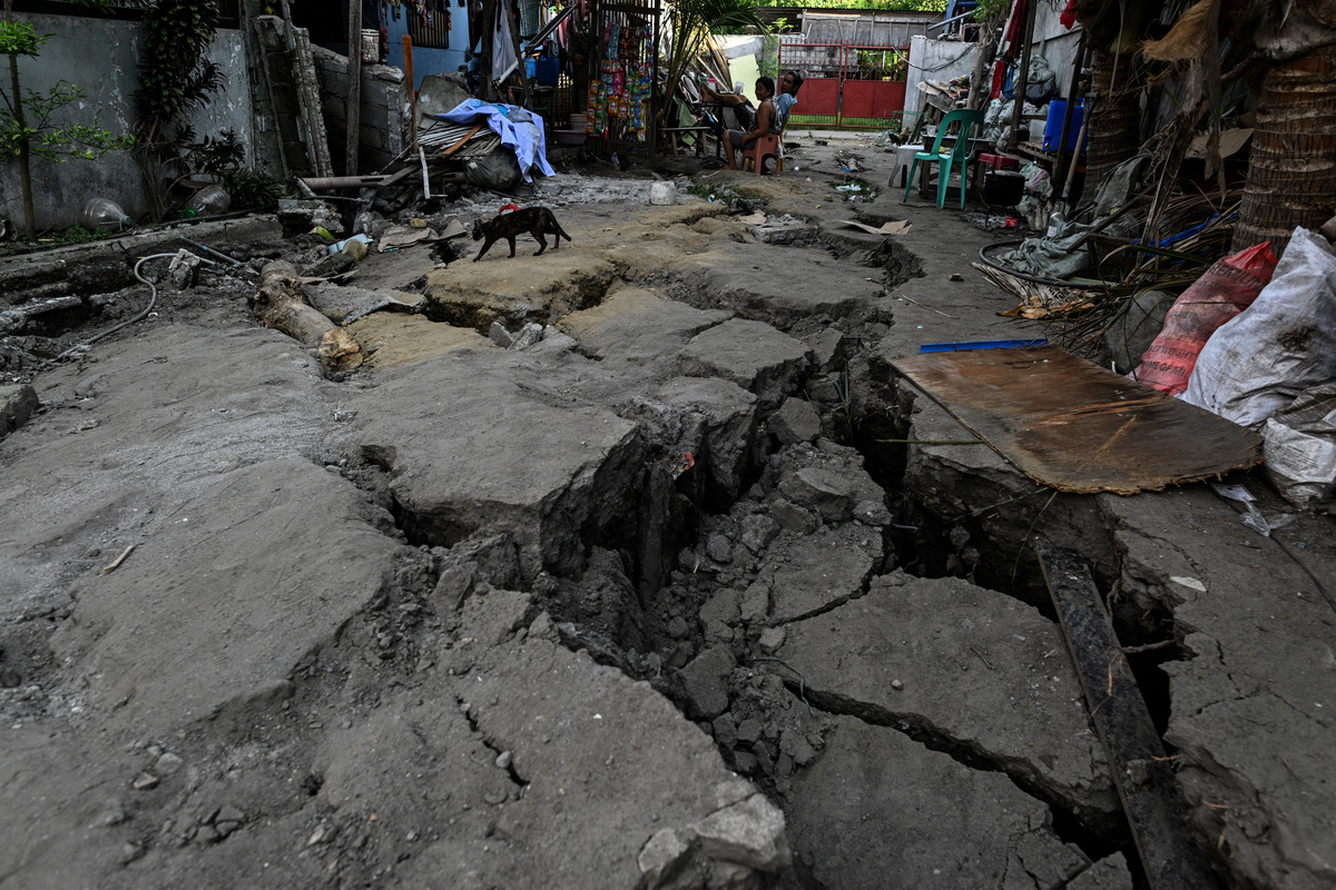 People sit outside their house on an earthquake-cracked street a day after the magnitude 7.8 quake in General Santos, southern Philippines, June 9, 2026. REUTERS/Noel Celis