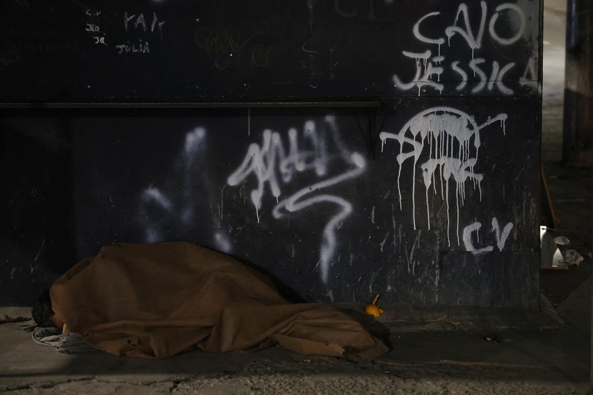 A person lies next to a wall with graffiti reading "C.V", referring to a Brazilian gang Comando Vermelho, in Jacarezinho slum in Rio de Janeiro, Brazil May 29, 2026. REUTERS/Aline Massuca