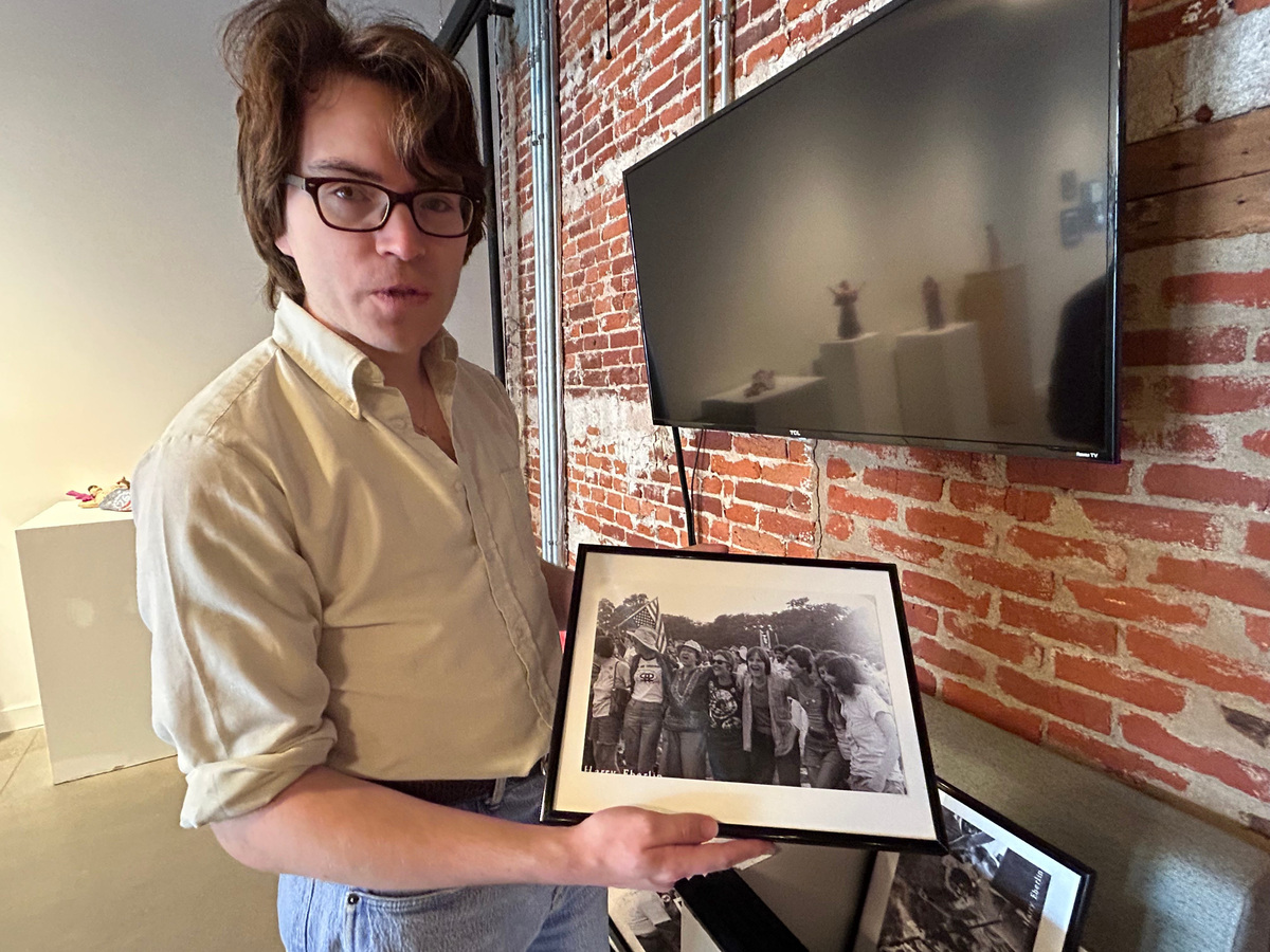 Jake Foster shows an archival photo from the William Way LGBTQ Community Center that is part of "This Is (Not) a Celebration," an exhibition about the LGBTQ+ reaction to the bicentennial in Philadelphia. Phaedra Trethan