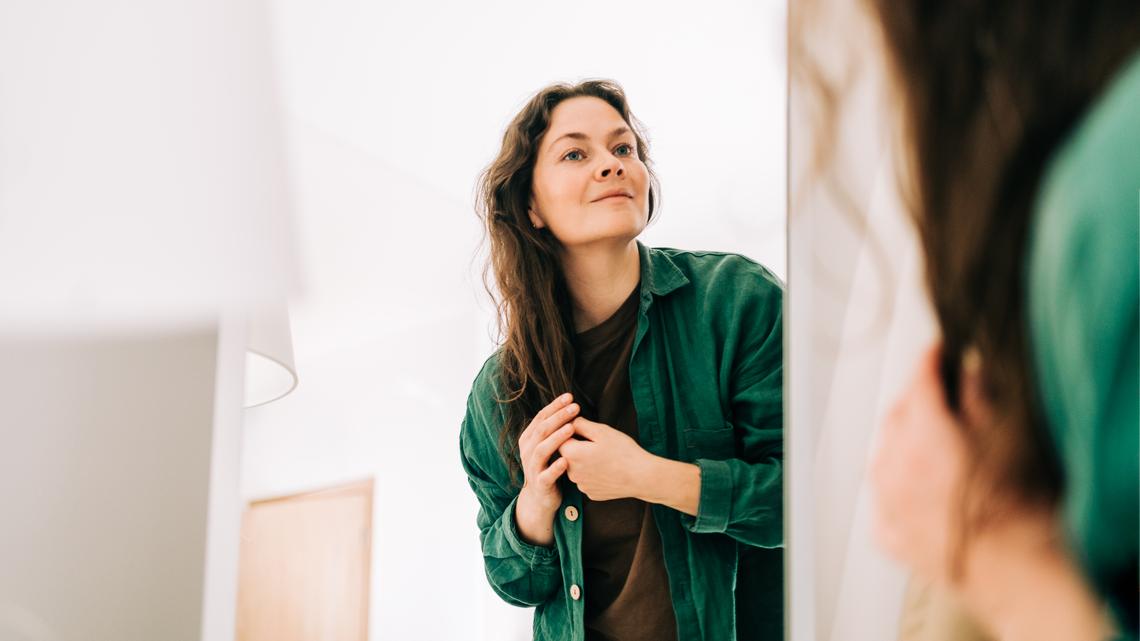Mid adult woman wearing casual clothes looking at herself in mirror