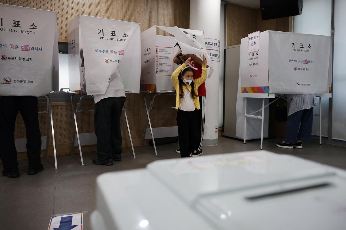 A man and his daughter leave a voting booth during the local elections at a polling station in Seoul, South Korea, June 3, 2026. REUTERS/Kim Hong-Ji