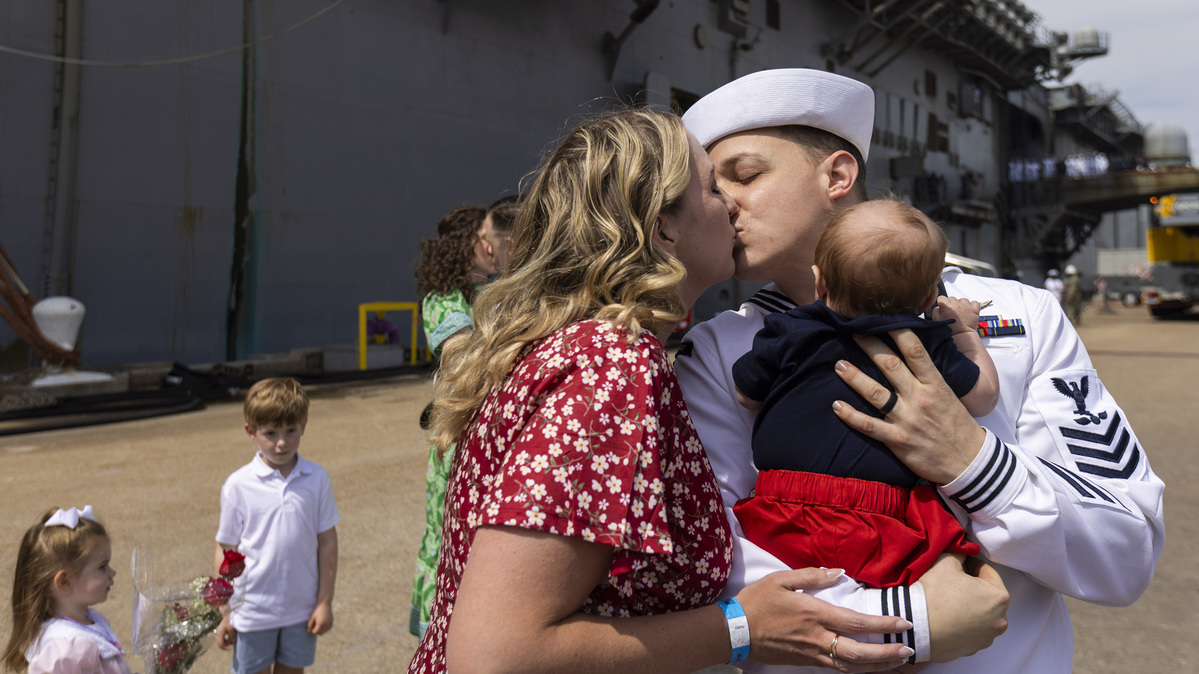 Aviation Ordnanceman Petty Officer 1st Class Andrew Hill holds his son, Mason, and kisses his wife, Lauren, after disembarking the USS Iwo Jima at Naval Station Norfolk on Saturday, June 6, 2026, in Norfolk, Virginia. (Peter Casey/The Virginian-Pilot/TNS)