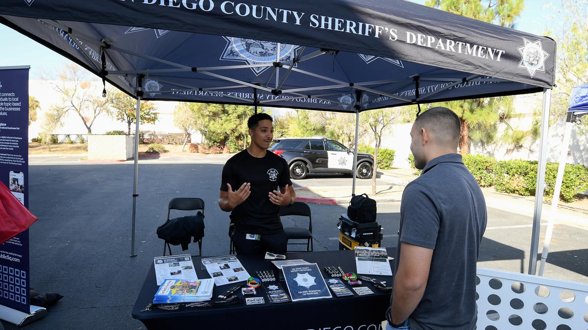 Job seeker Rueben Cota talks with recruiter San Diego sheriff's deputy Hubbard during a job fair for employees who are not vaccinated against the coronavirus disease (COVID-19), in Temecula, California, U.S., December 4, 2021. REUTERS/Denis Poroy