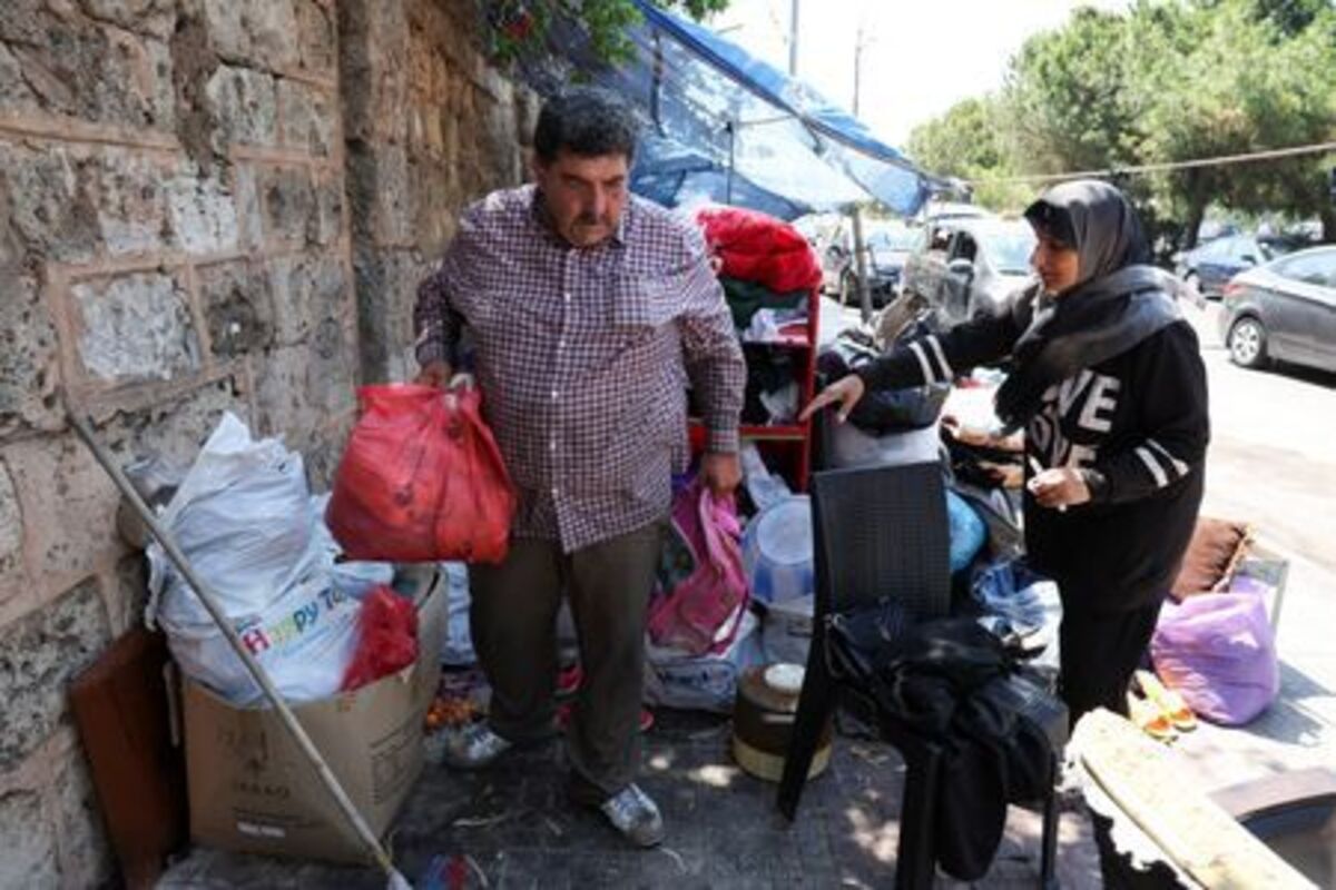 A man and his wife pack their belongings on a sidewalk in Beirut, where they have been living in a tent with their family, as they prepare to return home following an interim deal between the U.S. and Iran, in Beirut, Lebanon, June 24, 2026. REUTERS//Mohamed Azakir