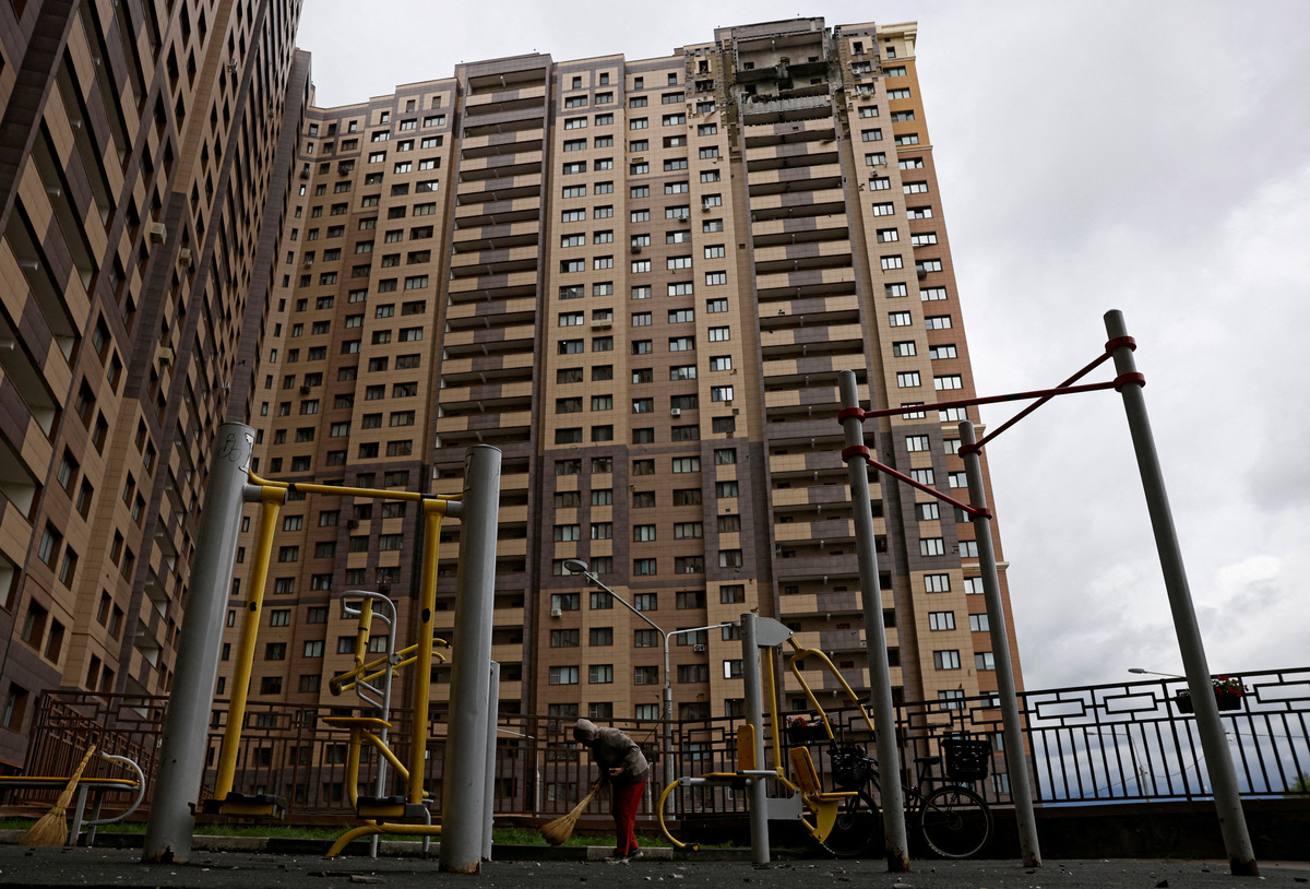 A person sweeps up debris in front of a damaged apartment building following a Ukrainian drone attack in the course of Russia-Ukraine conflict in Zhukovsky in the Moscow region, Russia June 18, 2026. REUTERS/Stringer