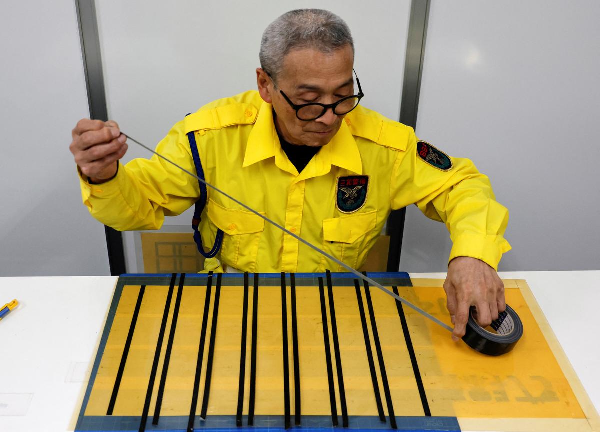 Shuetsu Sato, a security guard whose handmade duct-tape signs have gained widespread recognition, makes a duct-tape sign at a security company office where he works, in Tokyo, Japan, May 1, 2026.   REUTERS/Kim Kyung-Hoon