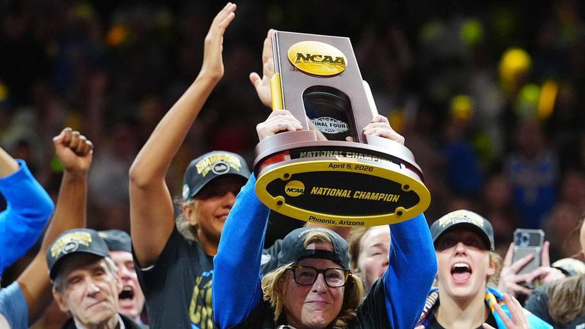  Apr 5, 2026; Phoenix, AZ, USA; UCLA Bruins head coach Cori Close celebrates with the trophy on the podium after defeating the South Carolina Gamecocks in the National Championship game of the women's 2026 NCAA Tournament at Mortgage Matchup Center. Mandatory Credit: Kirby Lee-Imagn Images | Kirby Lee-Imagn Images 