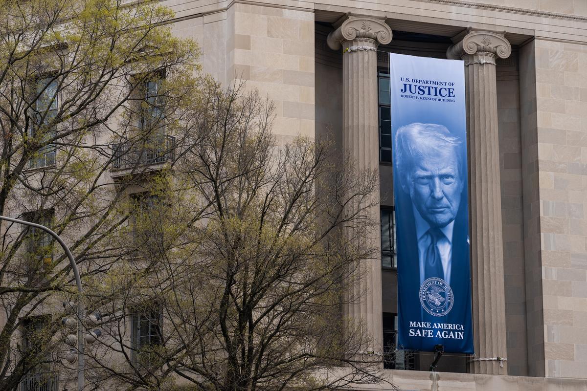 FILE -- A banner bearing the face of President Donald Trump hangs from the Department of Justice building in Washington, March 26, 2026. The Justice Department announced on Monday, May 18, that it was setting up a new $1.8 billion fund to compensate people who it said were victims of "weaponization and lawfare," a group that will almost certainly be made up of President Trump's political allies. (Eric Lee/The New York Times)