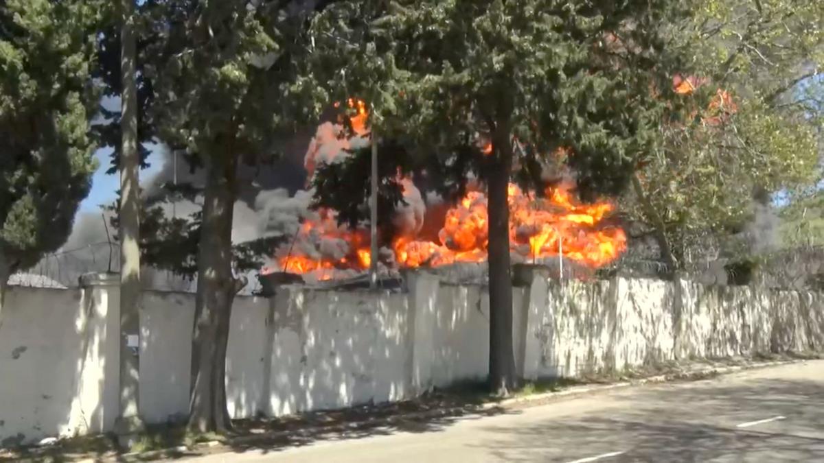 Smoke and flames rise behind a fence during a visit by Krasnodar region's Governor Veniamin Kondratyev, who inspects emergency services following a Ukrainian drone attack that caused a fire at an oil refinery, amid the Russia-Ukraine conflict, in Tuapse, Russia, April 28, 2026, in this still image taken from video. Governor of Krasnodar Region Veniamin Kondratyev/Handout via REUTERS