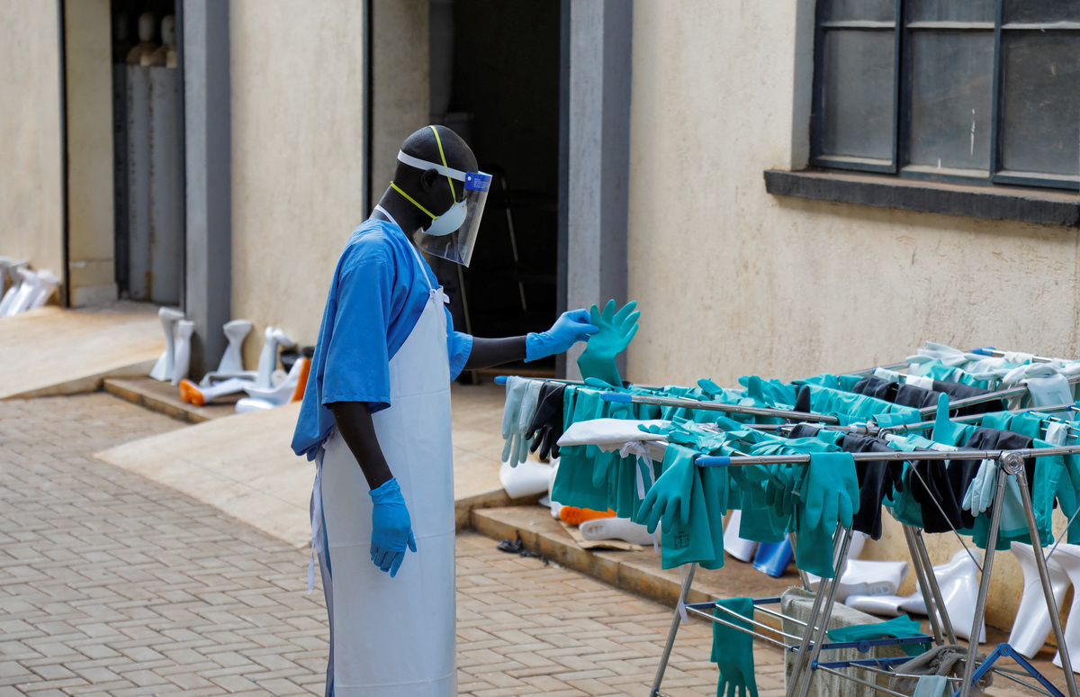 A Ugandan worker collects a rubber glove from the airing line during a visit by the Director-General of the World Health Organisation (WHO) Tedros Adhanom Ghebreyesus at the Mulago National Referral Hospital Isolation Unit, as aid agencies intensify efforts to contain a new Ebola outbreak involving the Bundibugyo Virus, in Mulago suburb, of Kampala, Uganda June 8, 2026. REUTERS/ Abubaker Lubowa