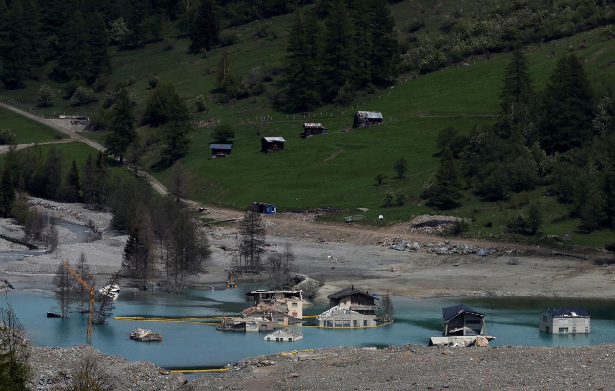 A few remaining houses stand nearly a year after a massive rock and ice slide, triggered by the collapse of the Birch Glacier, destroyed much of the village of Blatten, Switzerland, May 20, 2026. REUTERS/Stefan Wermuth