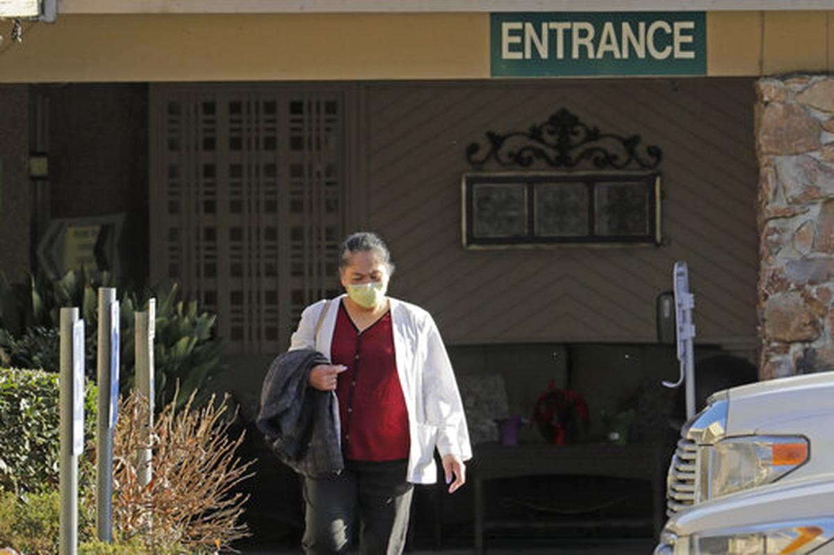 A worker at Life Care Center in Kirkland, Wash., near Seattle, wears a mask as she leaves the facility Friday evening, March 20, 2020. The nursing home has been at the center of the outbreak of the new coronavirus in Washington state.