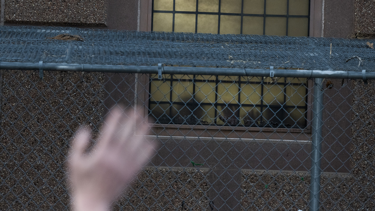 Detainees place their hands against a window outside the Aurora ICE Processing Center during a Passover Grief Vigil on Wednesday, April 8, 2026, in Aurora, Colo. (Timothy Hurst/The Denver Post/TNS)