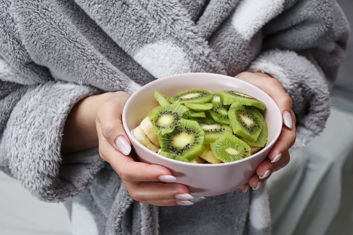  A stock image of a woman holding a bowl of kiwi. 